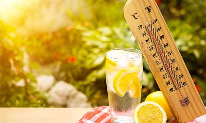 Thermometer indicating near 40 degrees resting on glass of water with lemon