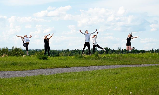 Group of young people jumping and dancing at a green space in the County