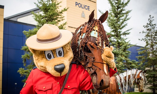 Safety bear giving a high-five to young kid wearing his helmet and holding his bike