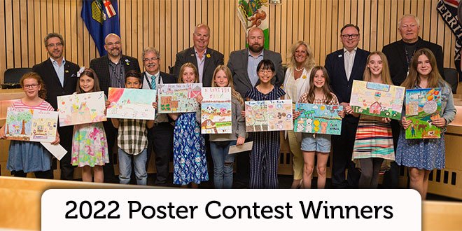 Poster contest winners holding up their posters with Council members standing behind them