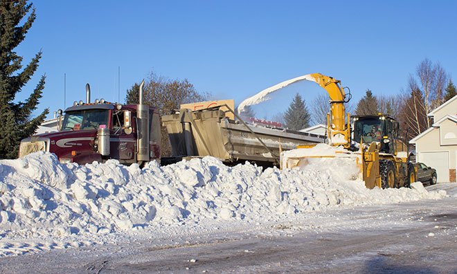 Snow clearing equipment blowing snow
