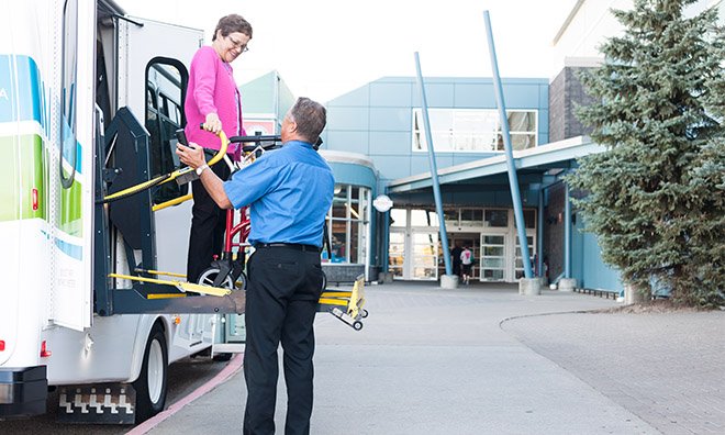 Bus driver assisting passenger to get off the mobility bus.