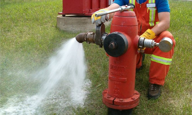 Image of a fire hydrant with water flowing out onto the ground.