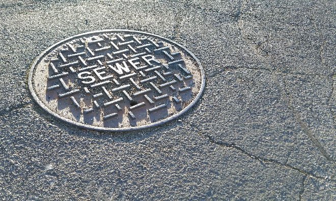 Image of a manhole cover with sewer written on the top