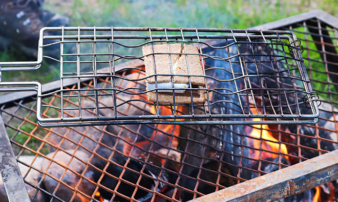 Smores being roasted over a screen-protected camp fire