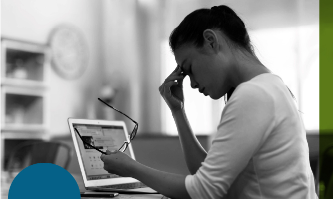 Black and white photo of woman at laptop holding forehead looking overwhelmed