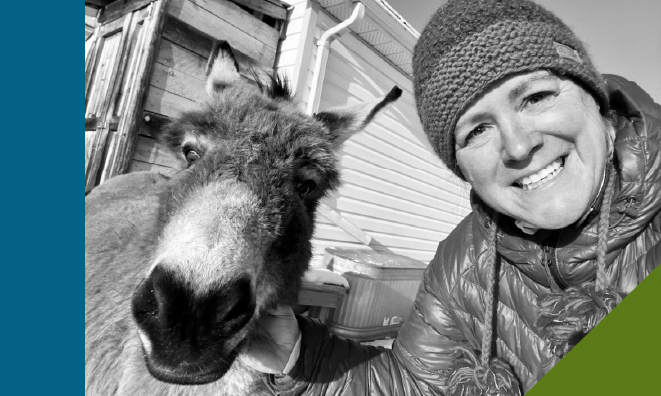 Black and white selfie photo of staff member Sherri outdoors in winter with her donkey, Daisy Mae