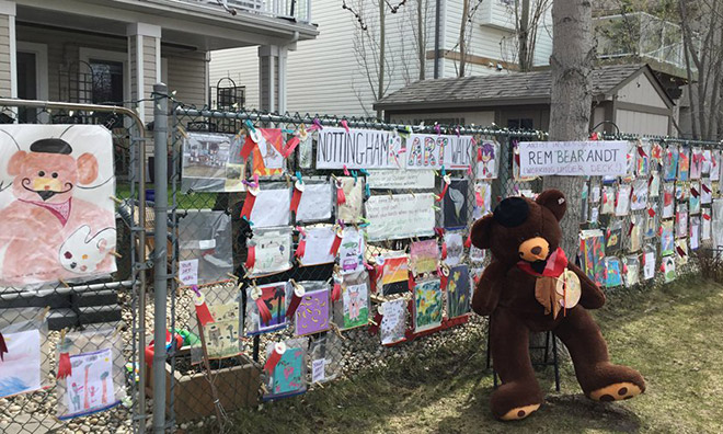 Drawings, messages and teddy bear on fence