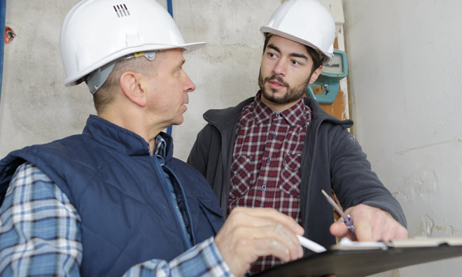 Two men wearing hard-hats going over a checklist