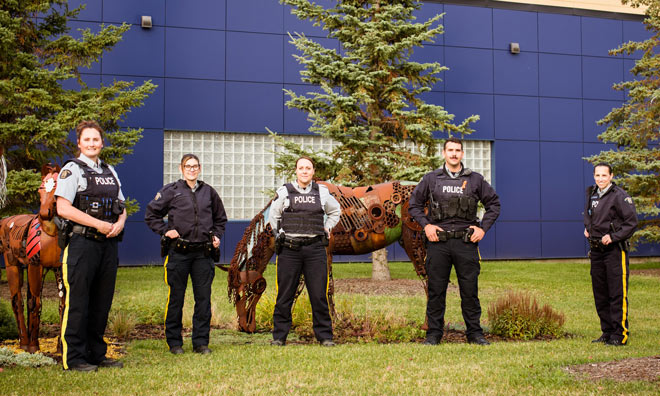 Police officers standing in front of the Strathcona County RCMP detachment.