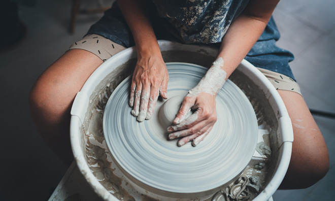 Photo of person creating pottery on a wheel