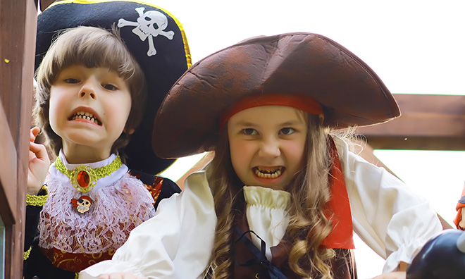 A young boy and girl making silly faces while wearing pirate hats