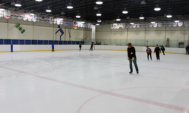 Large ice hockey arena with several people skating towards the foreground.