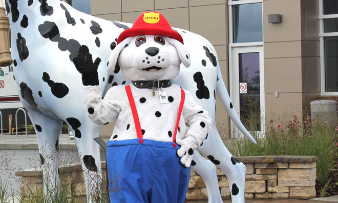 Sparky the fire safety dog posing in front of Saddie, the Emergency Services mascot dog sculpture at Fire Station 6.