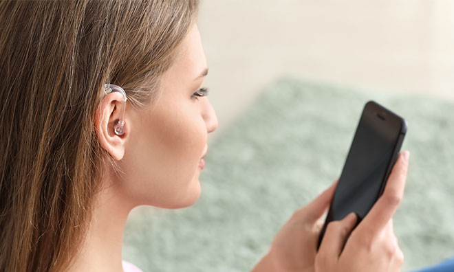 Woman with hearing aid using mobile to text 9-1-1