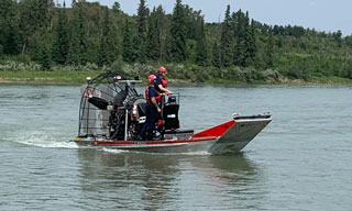 Firefighters in an air boat on the river