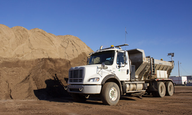 Sanding truck parked next to sand pile