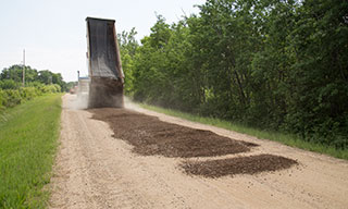 Truck dumping new gravel onto road