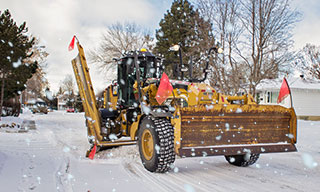 Grader clearing snow on a residential street.