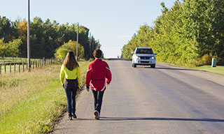 Two pedestrians walking along a rural road.