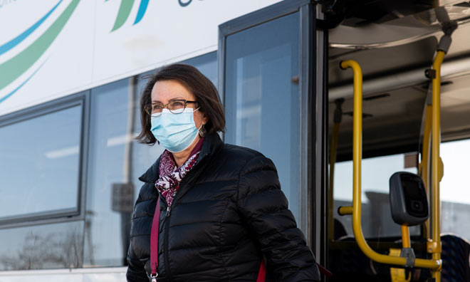 Masked woman exiting transit bus