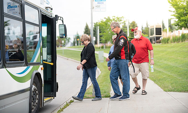 Group of four mature adults boarding a County bus in the summer