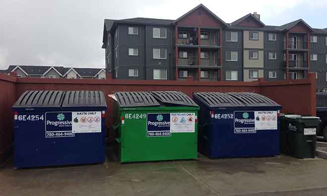 Waste and organics bins outside a multi-family building.
