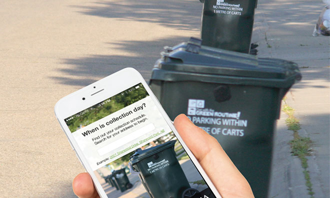 Close-up on hand holding a phone showing waste schedule on the screen. Waste cart in background.